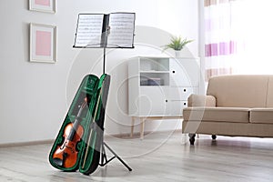 Violin in case and note stand with music sheets