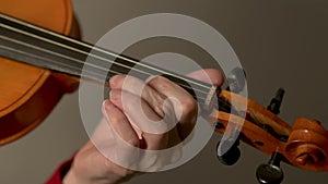 Violin in hands of a young female violinist during music performance. Close up view