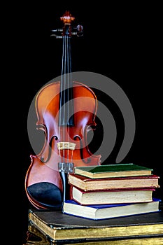 Violin with Old Books on a Reflective Black Surface and Black Background