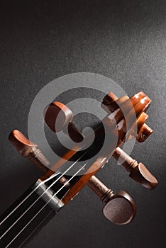 Violin pegbox on black textured table top vertical photo