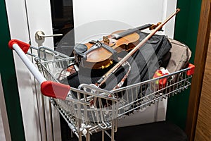A violin and various musician's items in a shopping cart