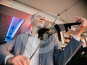 Violinist engages with electric violin, passion in his expression
