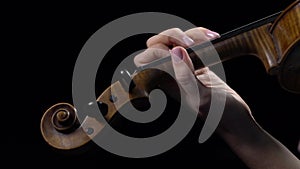 Violinist performs a composition on a violin. Black background. Close up