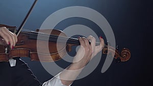 Violinist performs on a violin in a black smoke studio. Close up