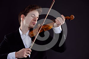 A violinist plays the violin in a Symphony orchestra concert, a musician emotionally plays classical music on a wooden instrument
