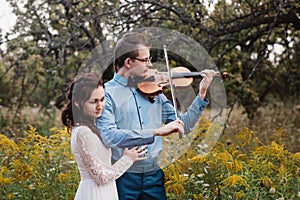 Violinist and woman in white dress , young man plays on the violin the background nature