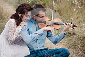 Violinist and woman in white dress , young man plays on the violin the background nature