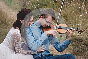 Violinist and woman in white dress , young man plays on the violin the background nature