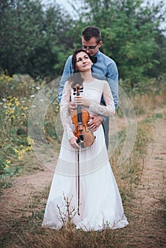 Violinist and woman in white dress , young man plays on the violin the background nature