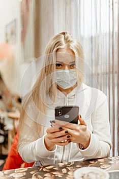 Viral mask. European blonde in flu mask for prevention. phone in hands emergency phone