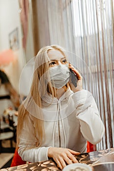 Viral mask. European girl in flu mask for prevention. Talking on the phone in a cafe