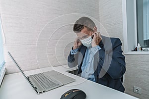 Viral threat, seasonal viral diseases. A man works in the office in a medical mask, protecting office workers from