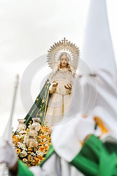 Virgin of Hope behind a penitent in the procession of the Brotherhood of the Virgin of Hope in Holy Week in Zamora, Spain