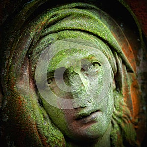 Virgin Mary. Ancient stone statue of sad woman in grief