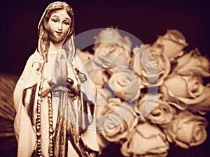 Virgin Mary mother of God praying rosary Christian statue statuette figurine and white roses