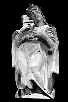 Virgin Mary Queen of heaven with baby Jesus Christ. Ancient stone statue isolated on black background