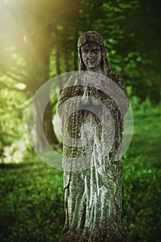 Virgin Mary statue. Very old and ancient stone statue of sad woman in grief