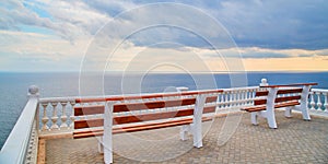 Virgin nature. Summer view. Ocean scenery. Viewing platform with bench. Empty promenade. Stormy dark sky. Calming sea