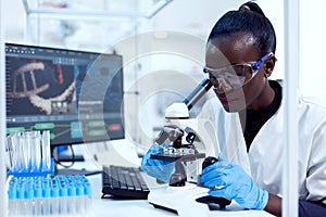 Virologist of african ethnicity sitting at her workplace neat test tubes