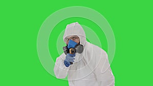 Virologist checks temperature with an infrared thermometer james bond parody on a green screen, chroma key.