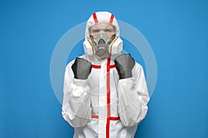 Virologist in a chemical protective suit holds his fists on a isolated background, man an epidemiologist, biologist, scientist