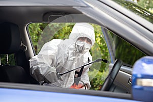 Virologist man wearing PPE kits kills bacteria and viruses inside the car.