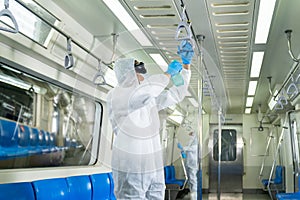 Virologists staff in hazmat suits cleaning disinfecting covid-19 in subway or sky train photo