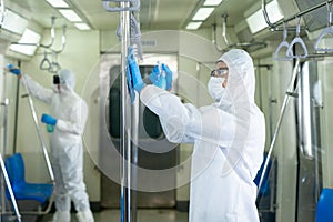 Virologists staff in hazmat suits cleaning disinfecting covid-19 in subway or sky train photo