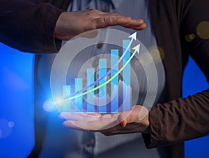 Virtual hologram of growth financial chart with increase arrow in businessman hands. Business success motivation development
