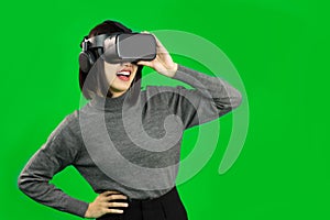 Virtual Reality concept. Happy young asian woman wearing VR headset looking at virtual screen, greenscreen