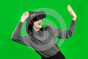 Virtual Reality concept. Young asian woman looking around, wearing a gray shirt and a VR headset, greenscreen