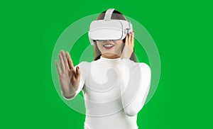 Virtual Reality concept. Young asian woman in white shirt with a VR headset touching on virtual screen, greenscreen