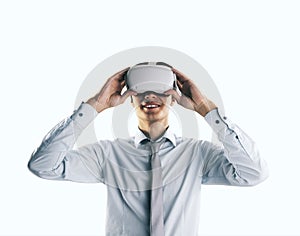Virtual reality concept with young businessman gets new emotions in VR glasses on his head on abstract white background, close up