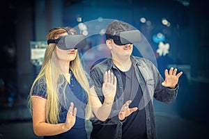 Virtual reality concept with young woman and man having fun with headset goggles during VR experience photo