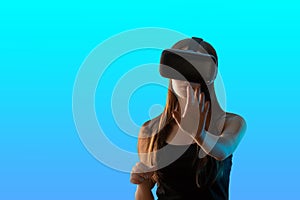 Virtual reality and the digital world. Girl gamer in VR helmet isolated on a blue background