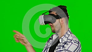 Virtual reality game. Girl with pleasure uses head-mounted display. Green scree. Close up