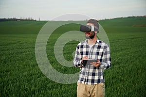 In virtual reality glasses. Handsome young man is on agricultural field