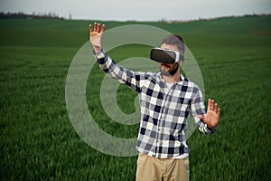 In virtual reality glasses. Handsome young man is on agricultural field