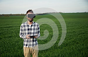 In virtual reality glasses. Handsome young man is on agricultural field