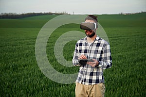 In virtual reality glasses. Handsome young man is on agricultural field