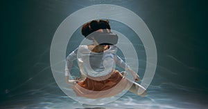 Virtual reality. Happy mixed race woman in augmented headset interface glasses floating deep under water slow motion.