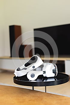 A virtual reality headset rests on a table in a modern living room with copy space