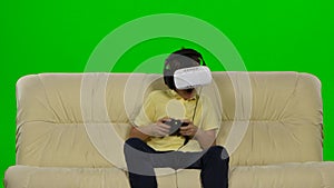 Virtual reality mask. The little boy with surprise and pleasure uses head-mounted display. Green screen