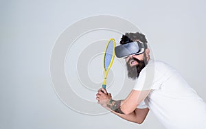 Virtual sport concept. Man with beard in VR glasses beating pitch, grey background. Hipster on busy face use modern