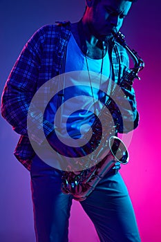 Virtuoso saxophonist, African American man, talented artist playing melody against gradient blue-pink background.