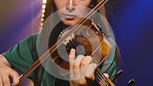 A virtuoso violin performed by a young woman. Hands of a female violinist close up. Slow motion.