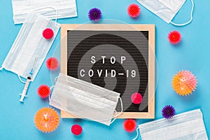 Virus COVID-19 protection concept. Virus abstract models with medical masks, syringe and letterboard with words Stop COVID-19 on