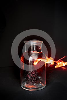 Virus hunted in a glass jar. Black background and bright red lights add drama