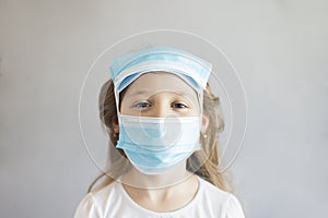 Virus protection concept. Close-up funny portrait of a cute girl in medical masks on her head and face