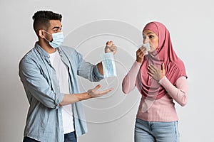 Virus Protection. Worry Arab Guy Giving Medical Mask To Sick Muslim Woman